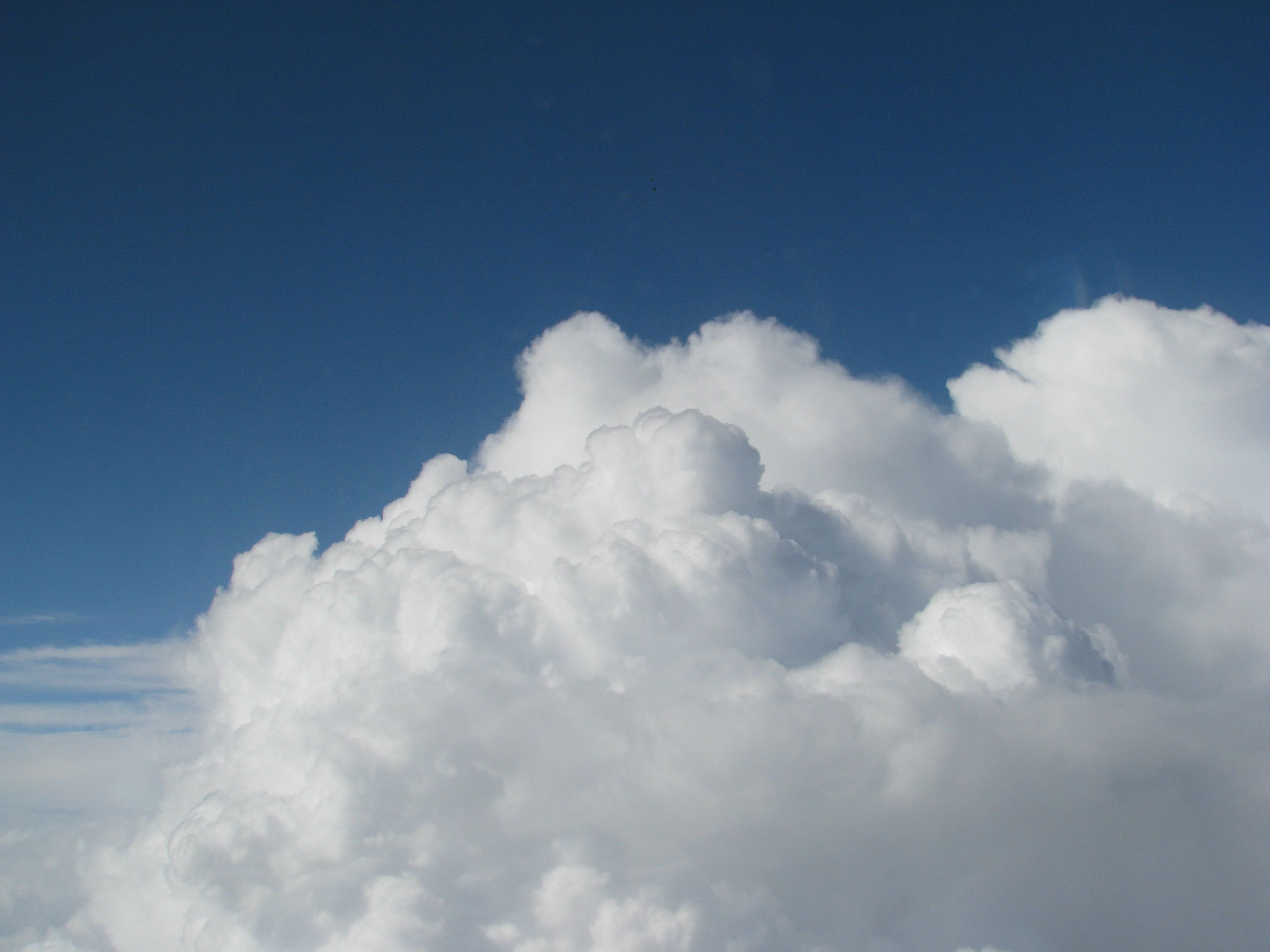 A photo of a blue sky with large white clouds in the foreground