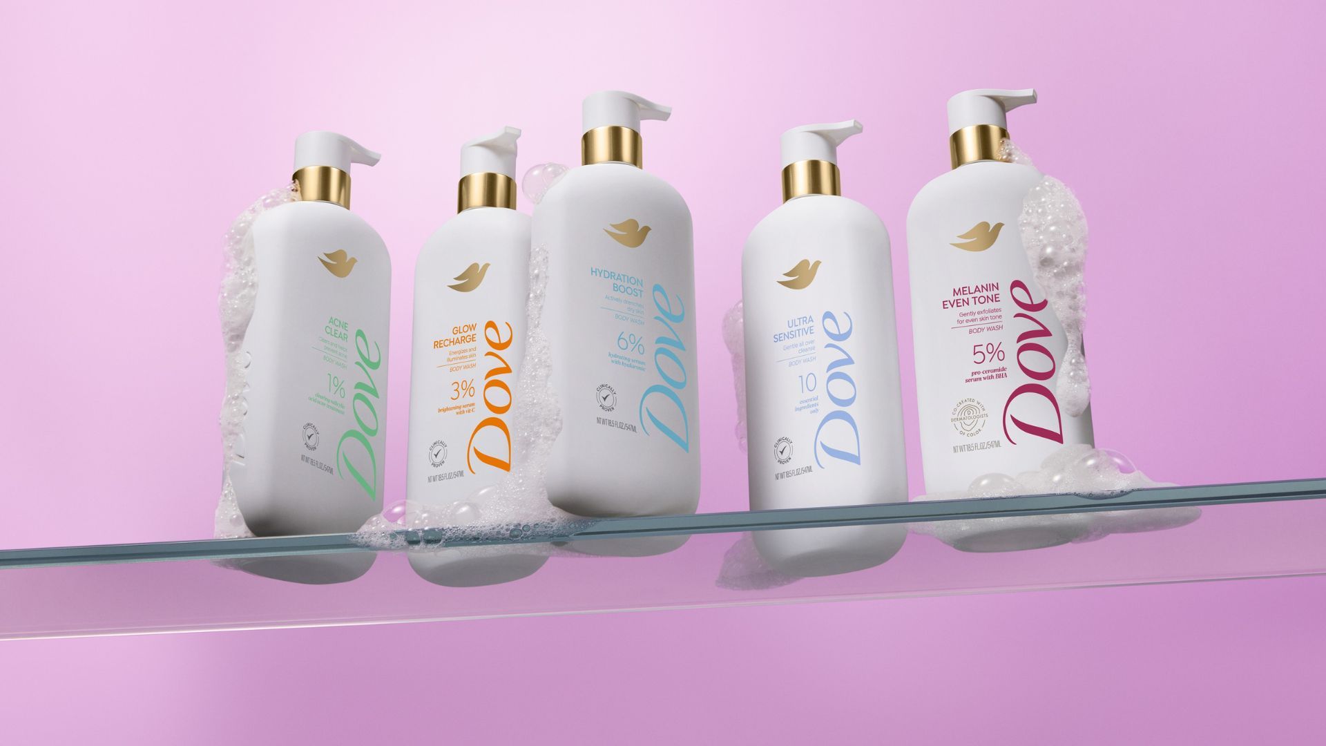 Five products from the Dove MicroMoisture-enriched body wash range. The bottles are white with gold accents and colourful branding, shot against a lilac background.