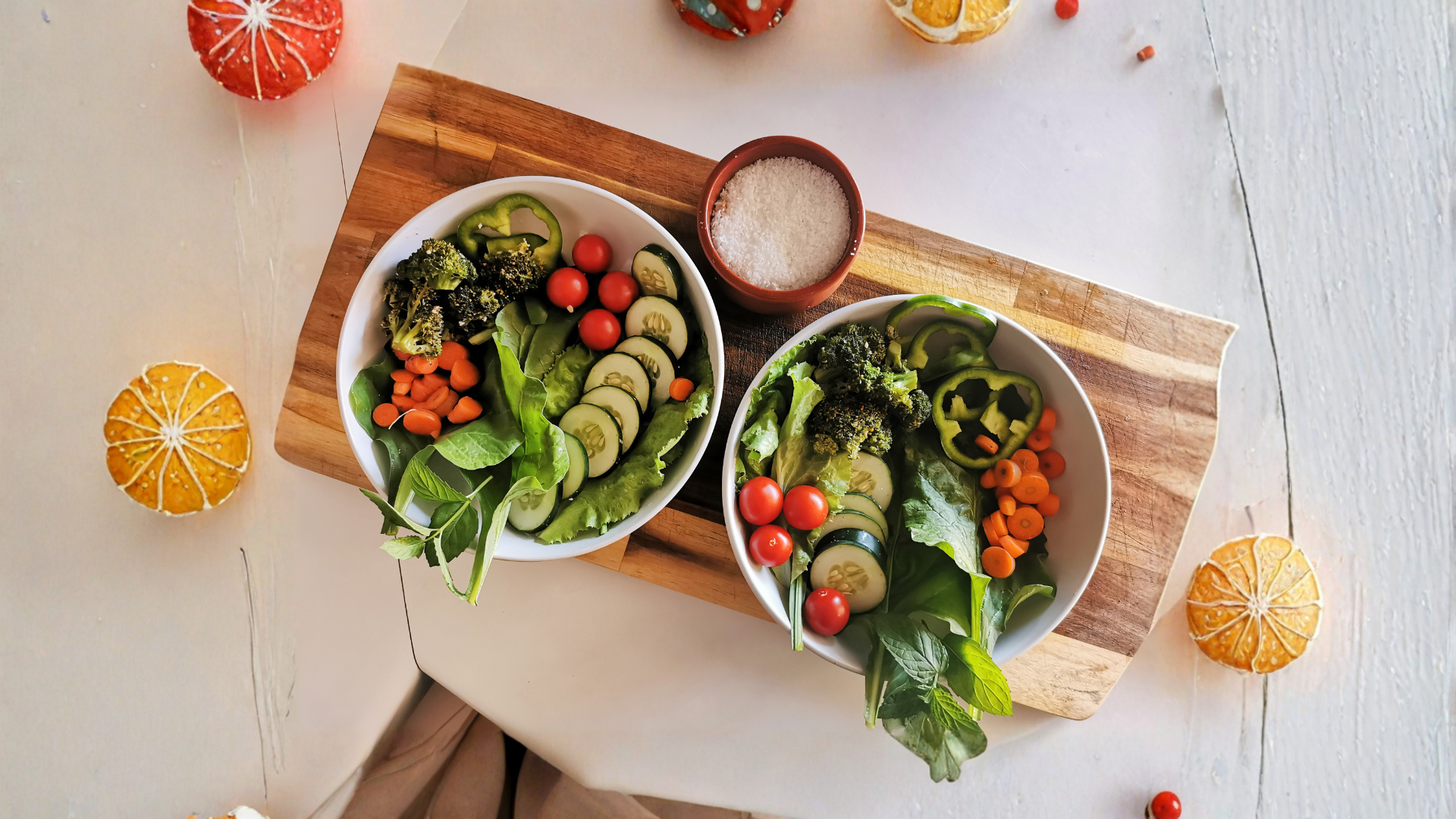 Two bowls of fresh salad on a wooden board.