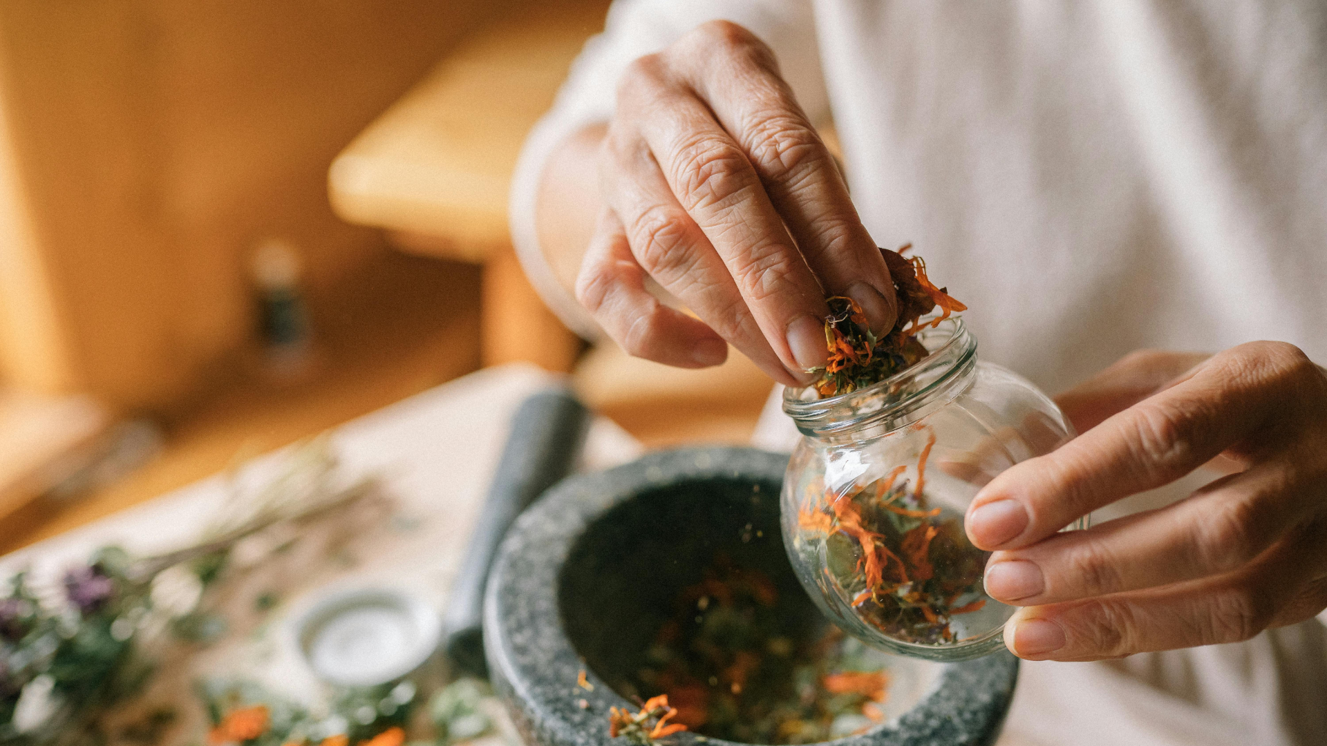 Person holding jar of dried herbs.