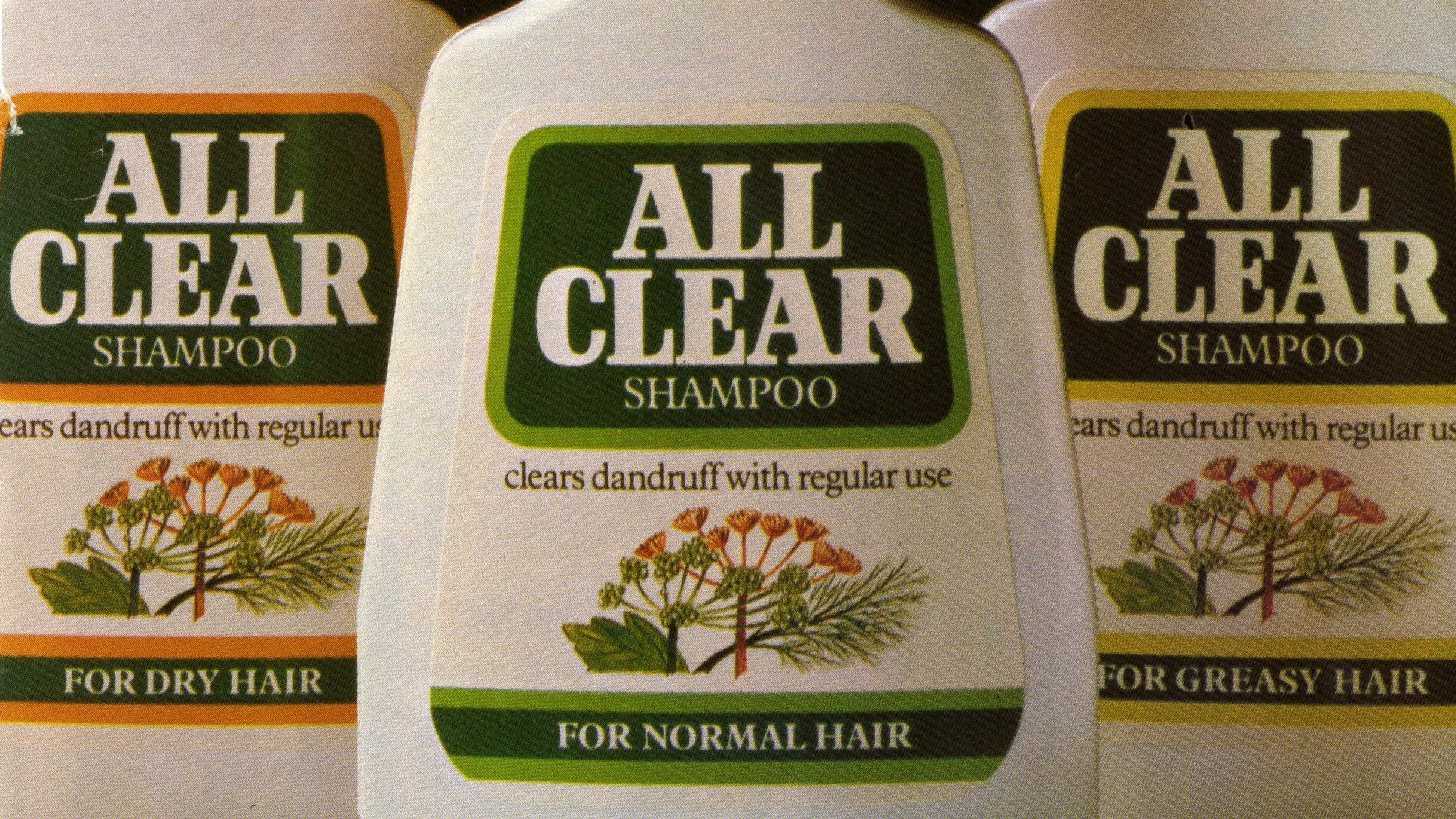 Three bottles of All Clear Shampoo, each designed for different hair types: Dry Hair, Normal Hair and Greasy Hair. The labels feature green branding with the text 'clears dandruff with regular use', along with an illustration of flowers and leaves on each bottle.