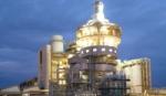 An illuminated factory tower against a dark blue night sky
