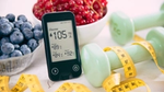Glucose meter with blueberries, red currants, green dumbbells, and tape measure.