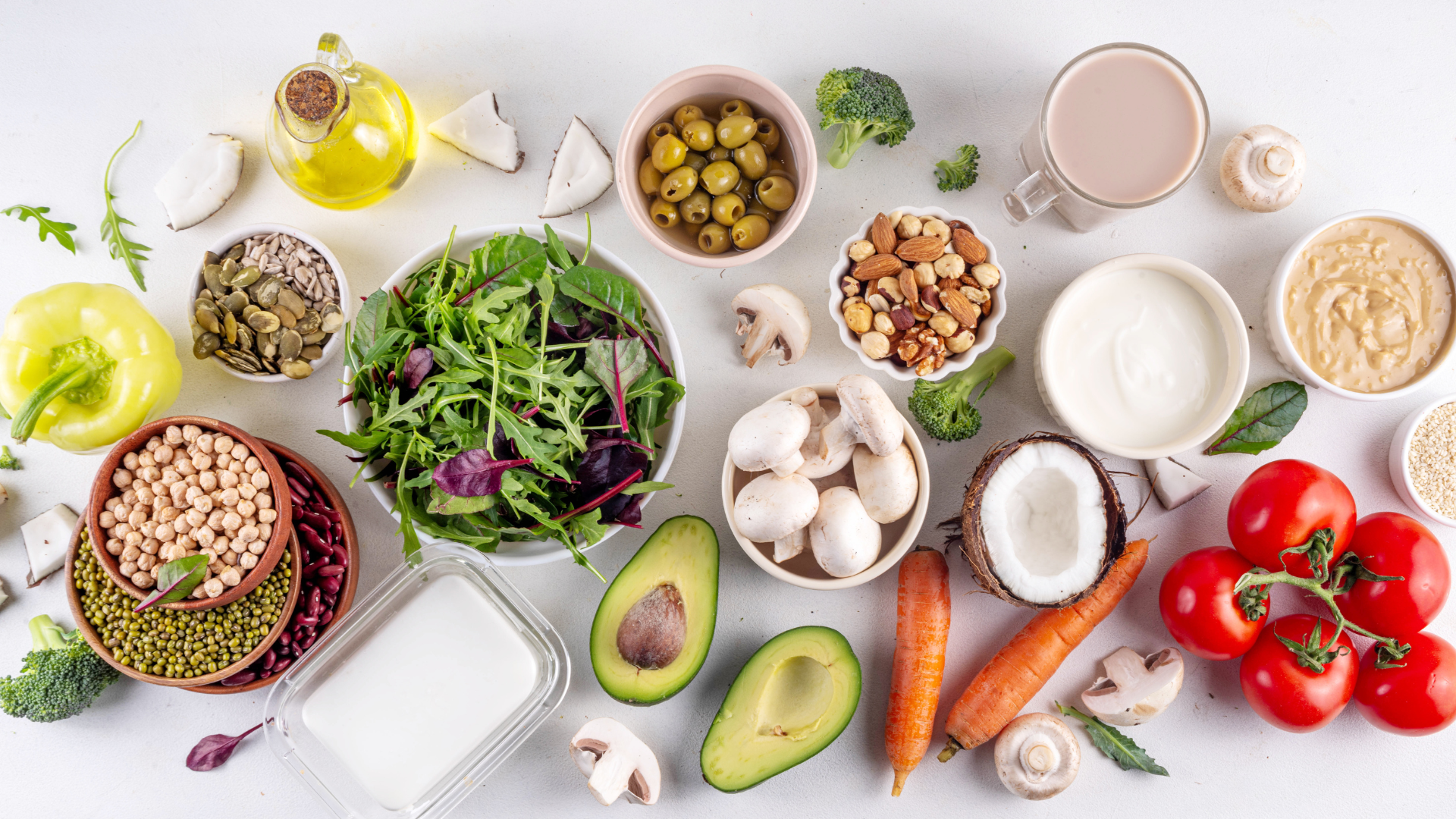 Various fresh vegetables, nuts, grains, and dairy ingredients arranged on a white background.