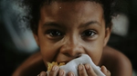 Child eating corn, holding cloth.