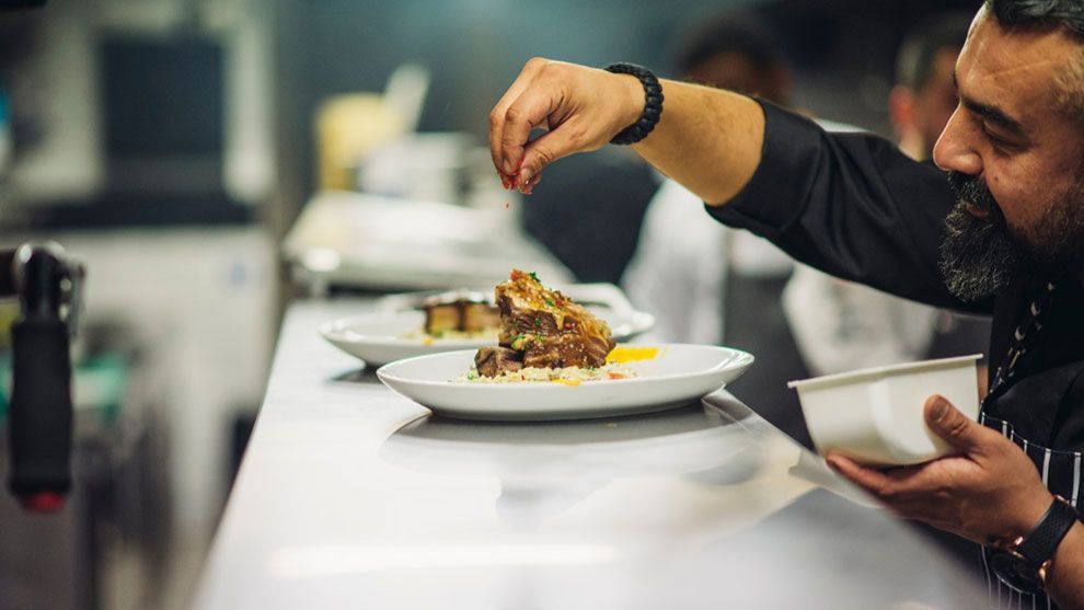 Chef adding final touches to plate of food