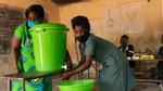 A green hand washing station is used by two women