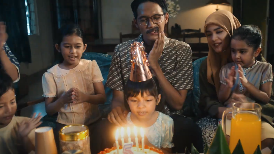A photo of a family at a birthday party. The father is clutching his jaw in pain from toothache.
