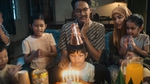 A photo of a family at a birthday party. The father is clutching his jaw in pain from toothache.