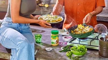 Man and woman cooking chicken dish using jar of Knorr product.