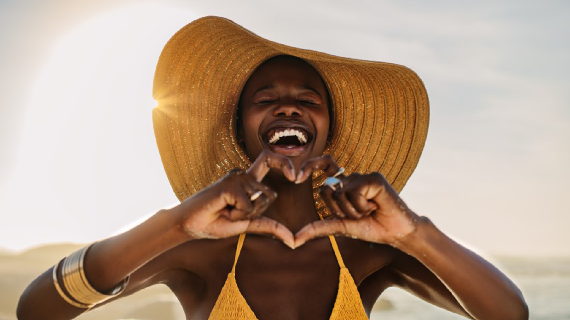 Woman making a heart sign with their hands and smiling