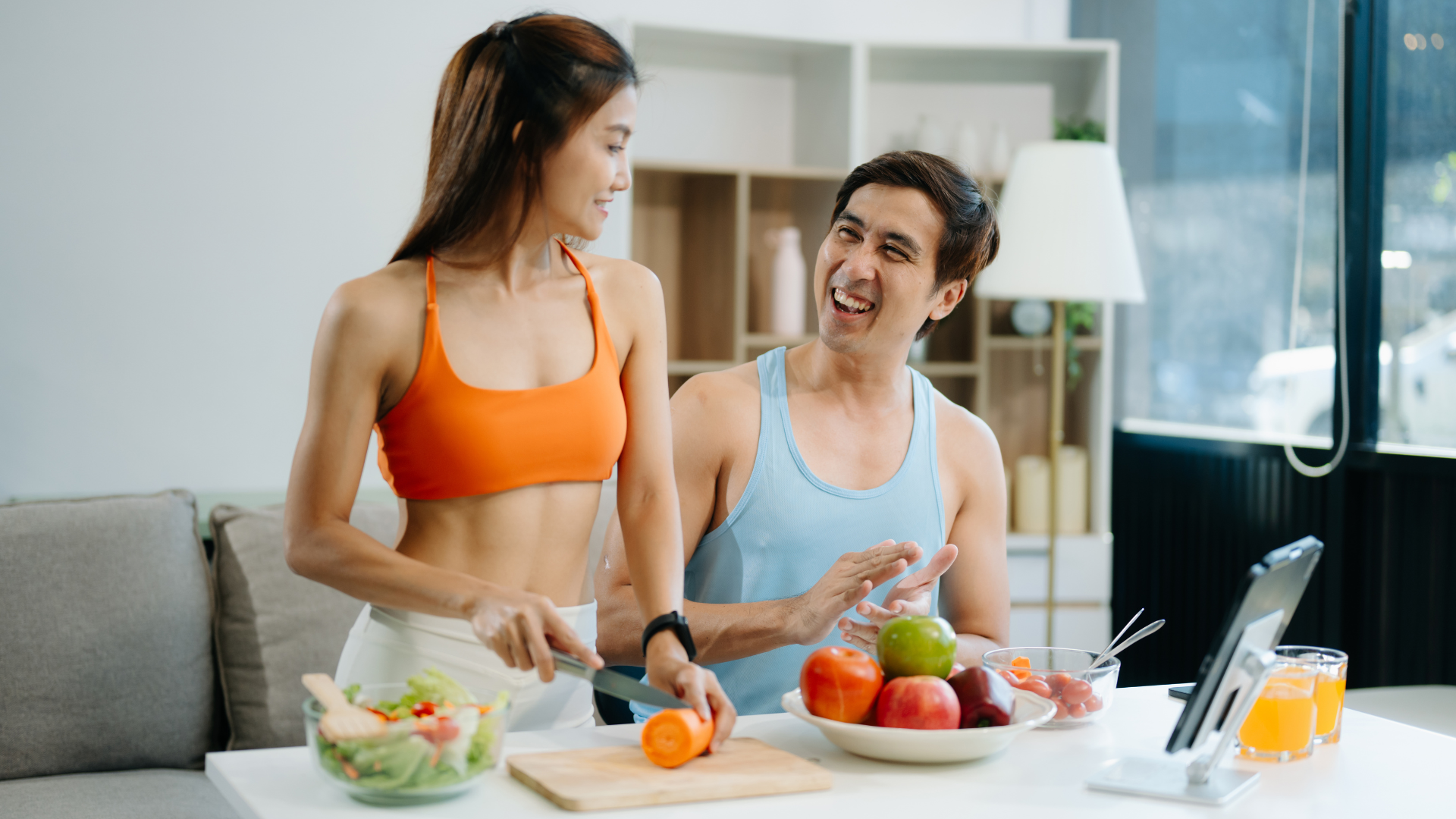 Couple in sportswear preparing healthy meal in kitchen.