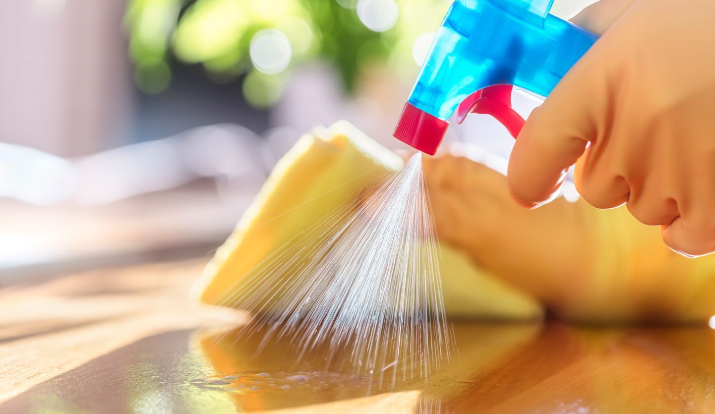 Close up of a cleaning product being sprayed and wiped down on a kitchen surface
