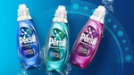 A blue, turquoise and pink bottle of Persil Wonder Wash on a teal backdrop.