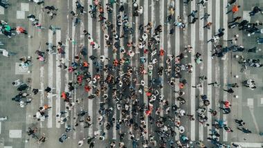Aerial view photograph of a large number of people crossing a road.