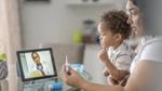 Woman with child on lap, discussing medicine with doctor via online appointment on her computer