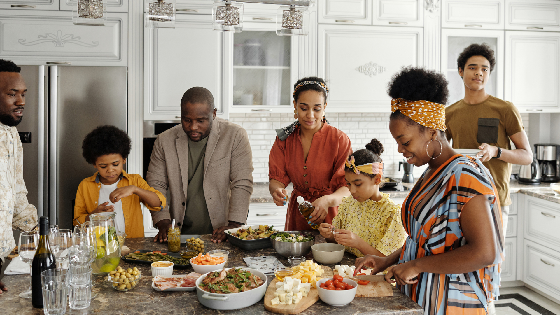 A family is gathered around a kitchen island, preparing a meal.