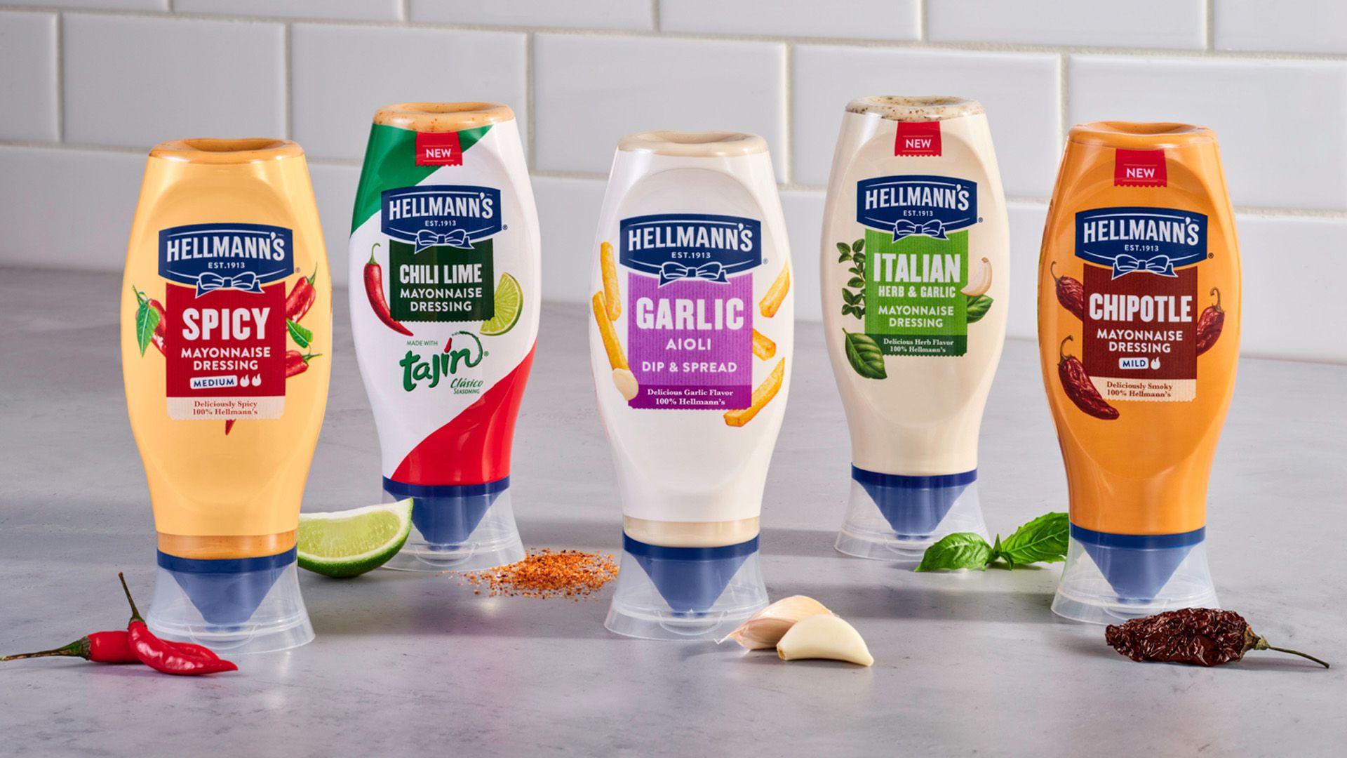 A line-up of Hellmann’s flavoured, squeeze bottle mayo's pictured with key ingredients like limes, chillies, garlic and herbs