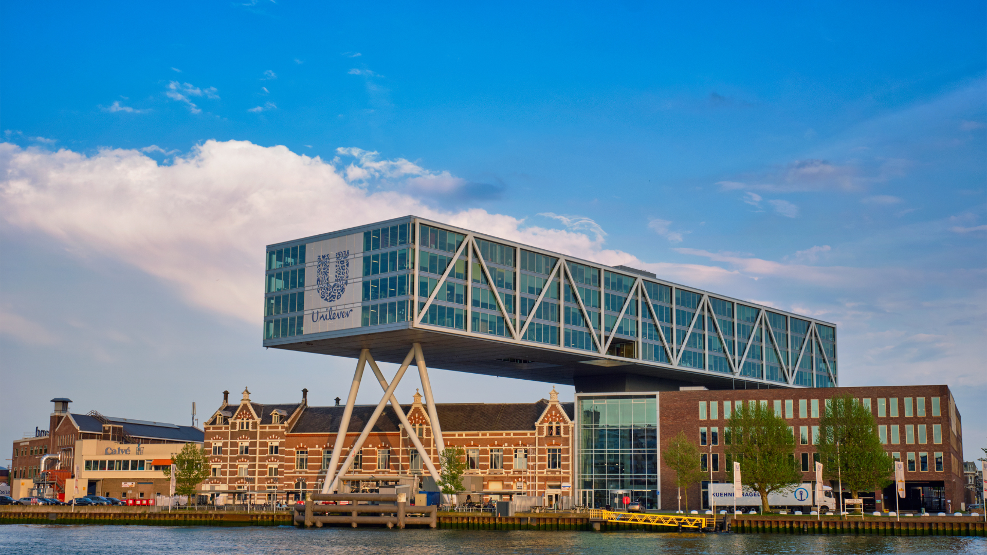 Modern building with glass facade over canal, blue sky.