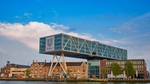 Modern building with glass facade over canal, blue sky.