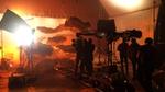 A film crew in a studio is setting up a shot of a large screen with floating grey and orange cut-out clouds.