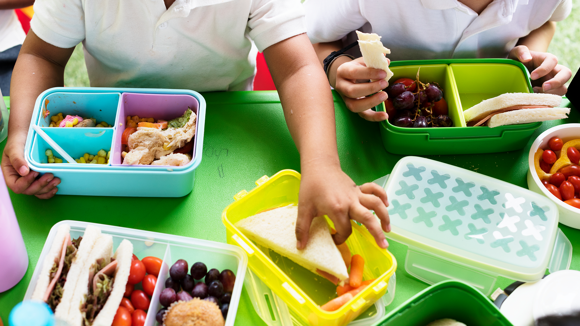 School children taking food out of their lunch boxes.