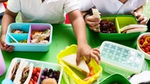 School children taking food out of their lunch boxes.