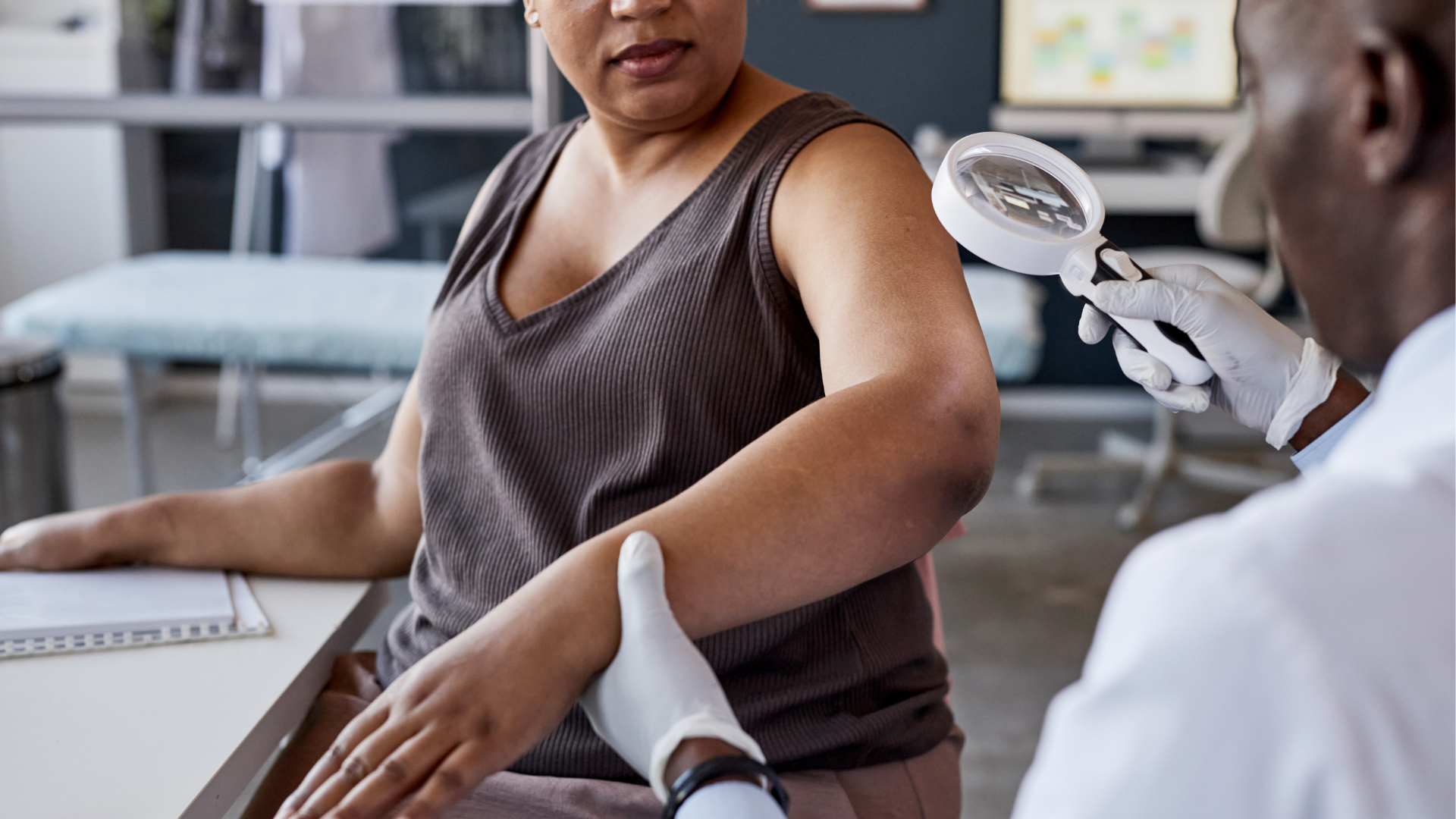 Doctor examining patient's arm with magnifying glass.